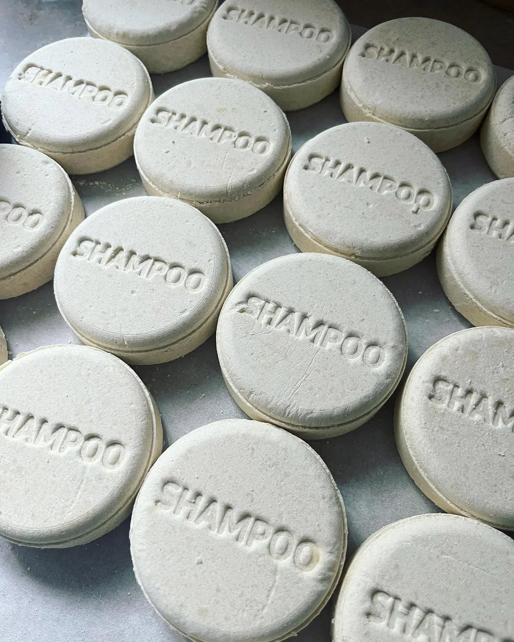 Multiple Lavish Earth lavender mint shampoo bars with 'SHAMPOO' printed on them, arranged on a flat surface.