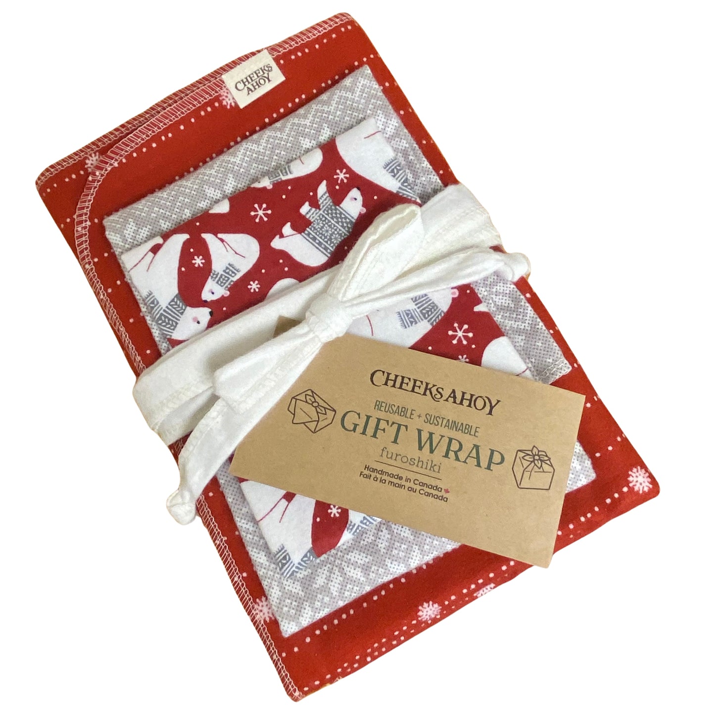 A set of reusable gift wrap in various red and grey patterns wrapped in a white reusable ribbon. There is a kraft paper tag attached that says 'CHEEKS AHOY REUSABLE + SUSTAINABLE GIFT WRAP' on the front.