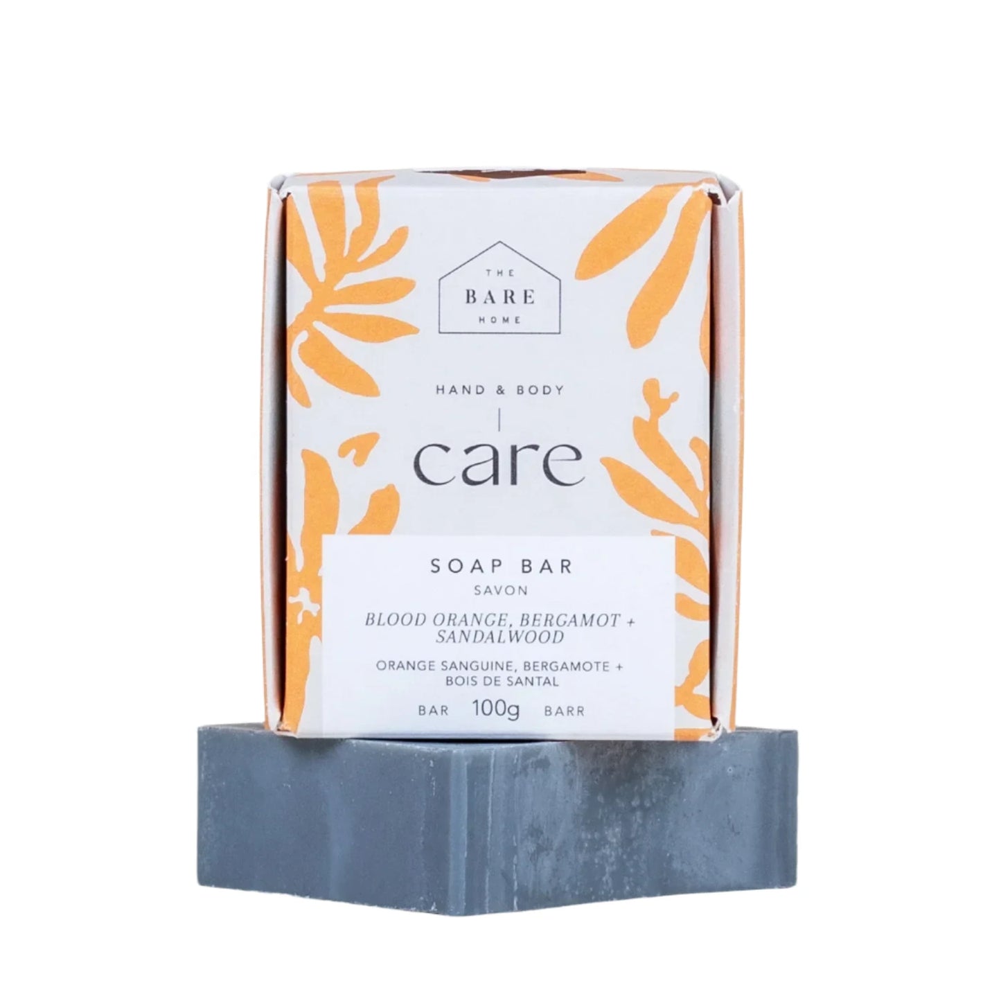 The Bare Home soap bar in the scent blood orange, bergamot and sandalwood. It is a dark grey bar infused with charcoal and the cardboard packaging is sitting atop it.