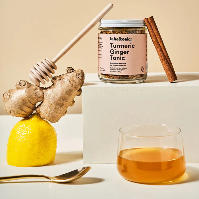 Turmeric Ginger Tonic jar with ingredients like ginger root, lemon, and cinnamon on a beige background